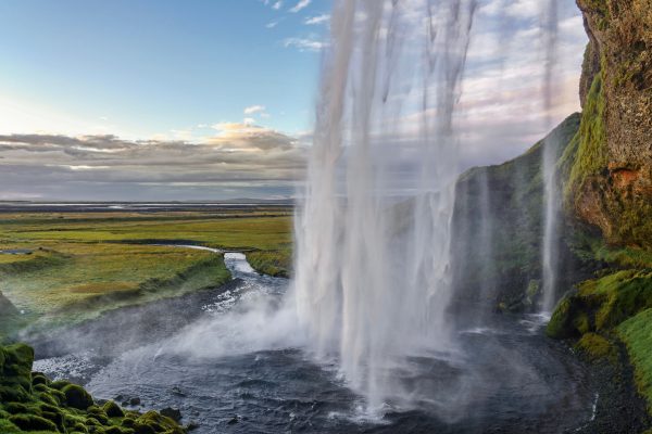 Stunning view of Seljalandsfoss waterfall in Iceland with vast fields during sunset. Nature 4K