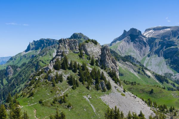 Stunning view of the jagged peaks and lush greenery of the Swiss Alps under a clear blue sky. Nature 4K