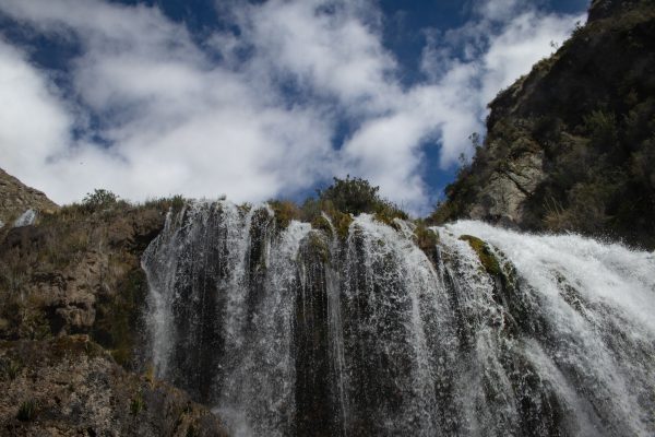 Stunning waterfall cascading down rocky cliffs beneath a partly cloudy sky, showcasing nature's beauty. Nature 4K