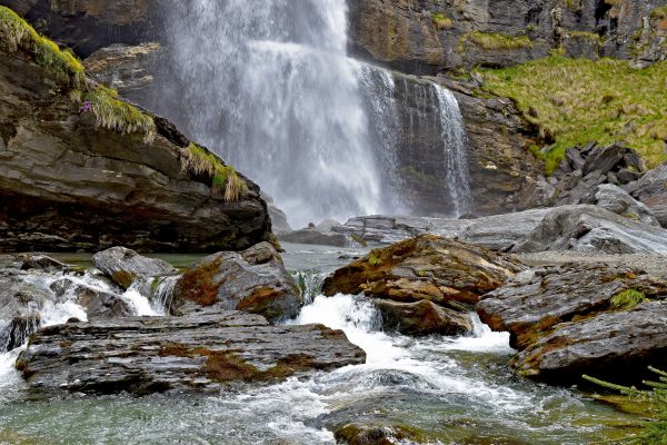 Stunning waterfall cascading over rugged rocks in a tranquil nature setting. Nature 4K