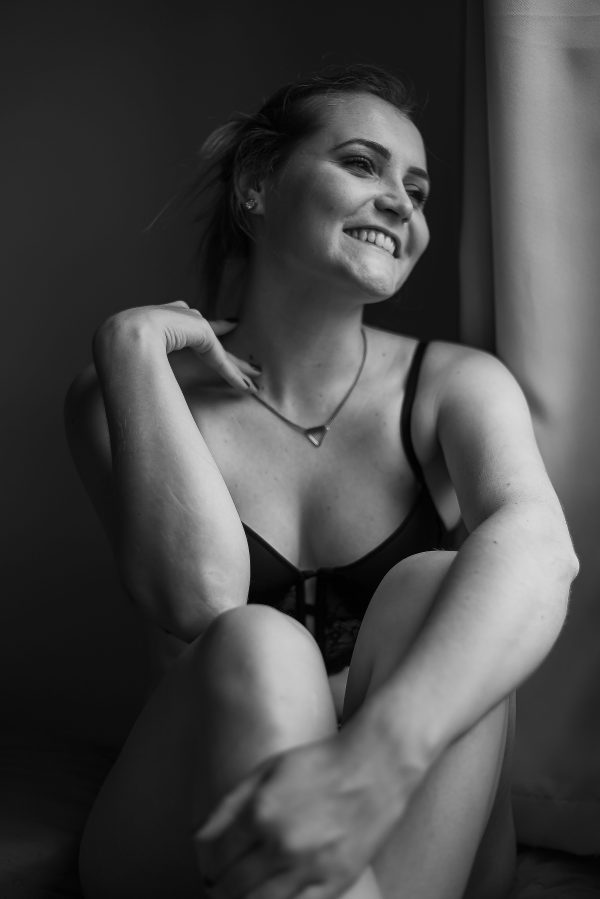 Stylish black and white portrait of a woman in lingerie, smiling and relaxed. Mobile 4K