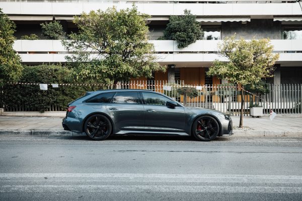 Stylish grey car parked by trees on a modern city street with a residential building backdrop. Voitures 4K