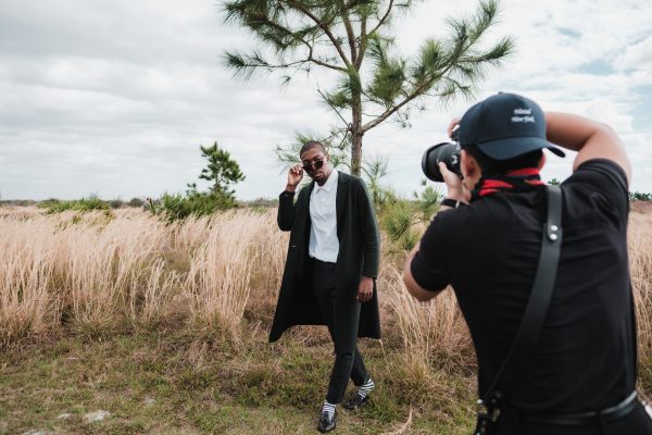 Stylish man posing in open field during outdoor photoshoot. Charme 4K