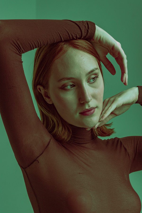 Stylish photo of a redhead woman posing in a brown turtleneck with dramatic lighting. Mobile 4K