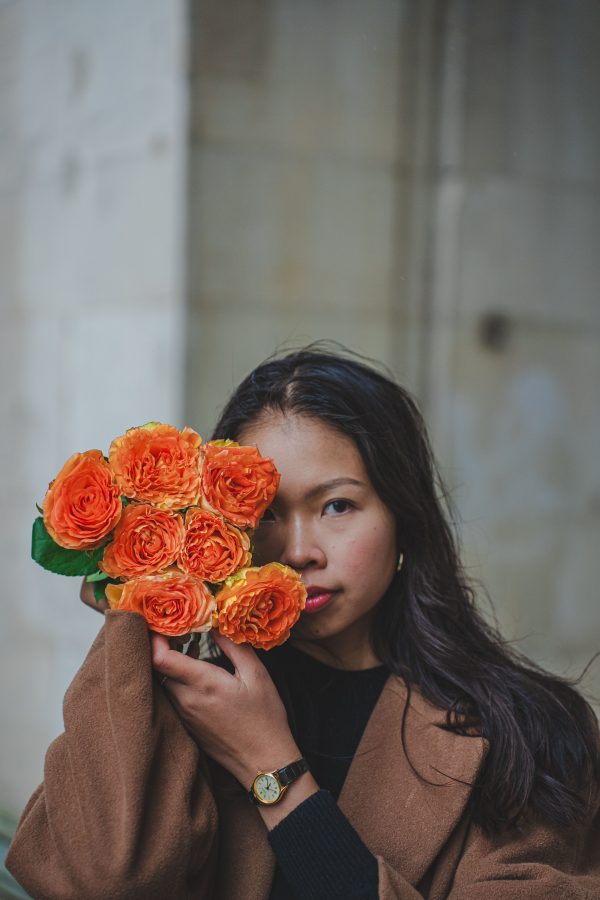 Stylish portrait of a woman holding orange roses in Munich, Germany. Mobile 4K