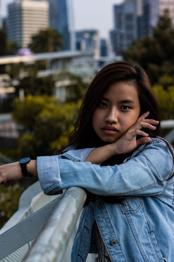 Stylish woman in denim jacket posing thoughtfully on urban balcony. Mobile 4K