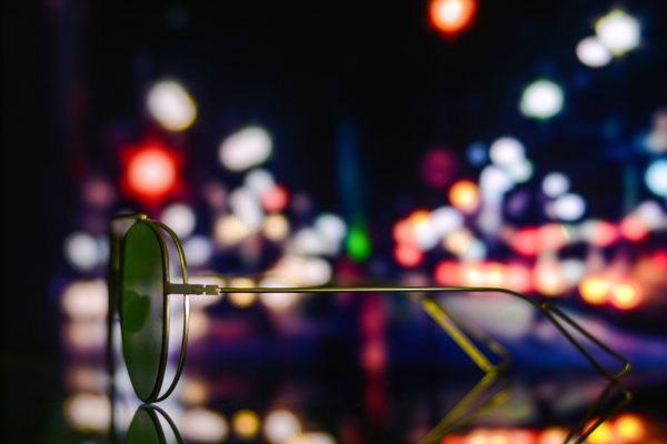 Sunglasses reflecting vibrant, defocused city lights at night creating a colorful urban ambiance. Voitures 4K