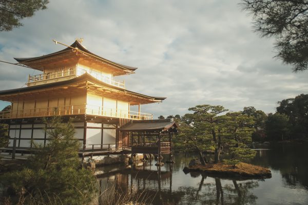 The Kinkaku-ji Temple in Kyoto, Japan, gleaming gold in sunlight and mirrored on still waters. Anime 4K