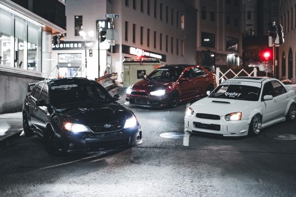 Three modified cars parked on an urban street at night showcasing automotive style. Voitures 4K