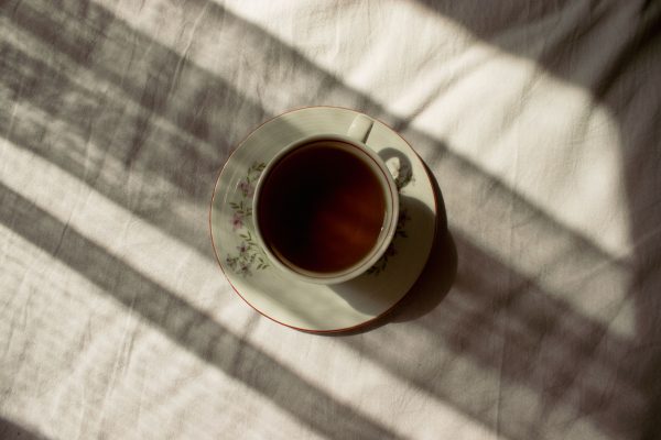 Top view of a tea cup with floral design casting shadows on linen. Minimaliste 4K