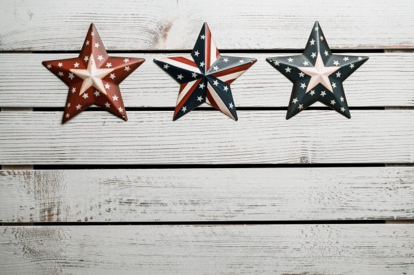 Top view of row of figurines of red and blue raised stars on white striped wooden table Espace 4K
