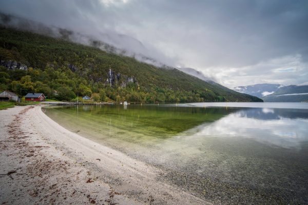 Tranquil fjord with mountains and cloudy sky in Norway, reflecting in calm waters. Nature 4K