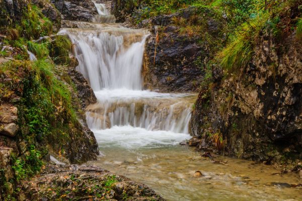 Tranquil scene of a cascading waterfall surrounded by lush greenery in Valmadrera, Italy. Nature 4K