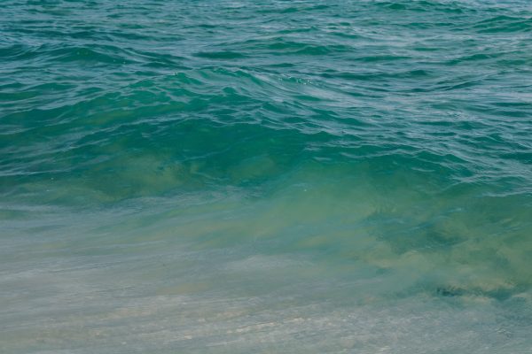 Tranquil turquoise ocean waves gently rolling onto a sandy beach on a sunny summer day. Nature 4K