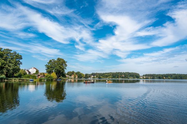 Tranquil view of a lakeside village with boats and reflections under a vibrant sky. Nature 4K