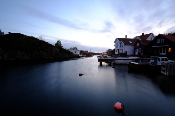 Tranquil waterfront scene at dusk with boats, houses, and reflective water under a picturesque sky. Nature 4K