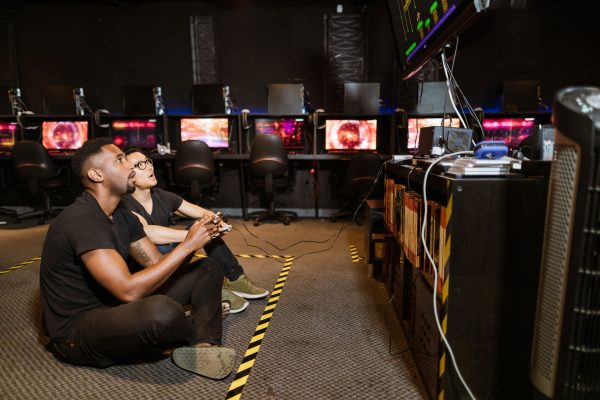 Two diverse men focused on gaming in a modern arcade setting, showcasing technology and camaraderie. Gaming 4K