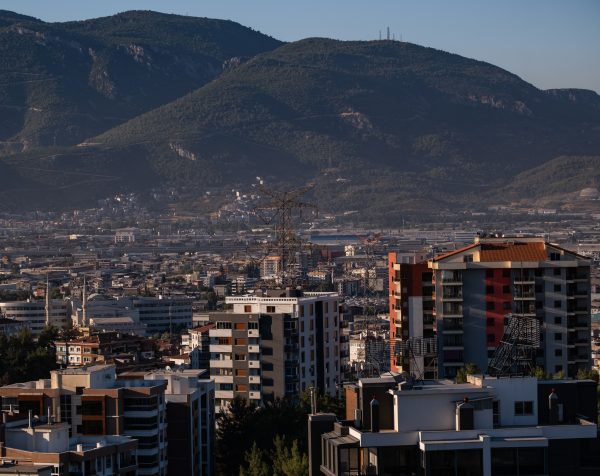 Urban landscape of İzmir featuring modern buildings and scenic mountain views under a clear blue sky. Nature 4K