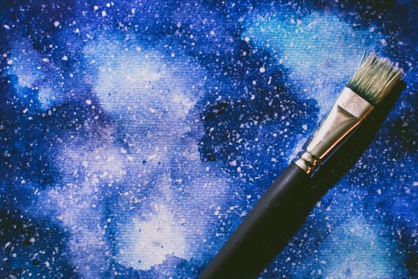 Vibrant abstract watercolor art with a paintbrush lying on a textured blue canvas. Espace 4K