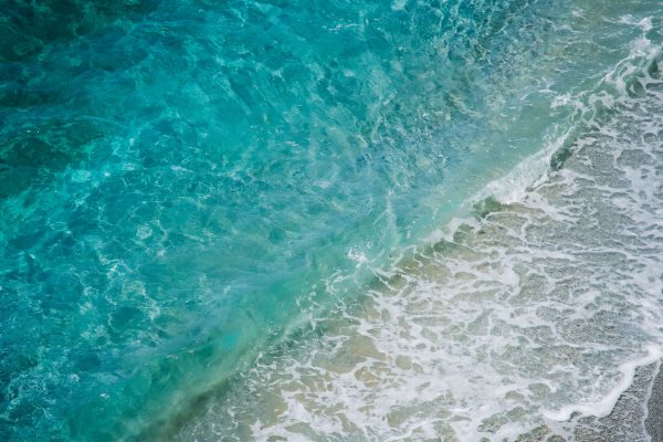 Vibrant aerial view of turquoise ocean waves crashing onto a sandy shore, showcasing the beauty of nature. Nature 4K