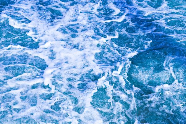 Vibrant blue ocean waves with frothy white foam creating a dynamic, textured seascape. Nature 4K