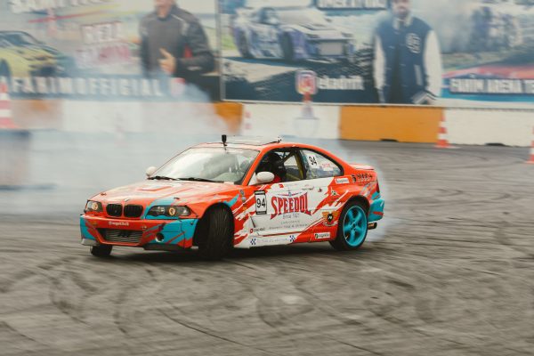 Vibrant drift car in a dynamic maneuver at an outdoor racing event, emitting tire smoke. Voitures 4K