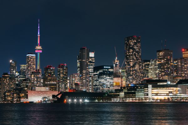 Vibrant night view of Toronto skyline featuring the illuminated CN Tower reflecting on the water. Architecture 4K