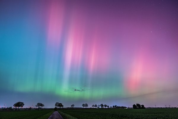 Vibrant Northern Lights illuminate a tranquil rural landscape at night. Espace 4K