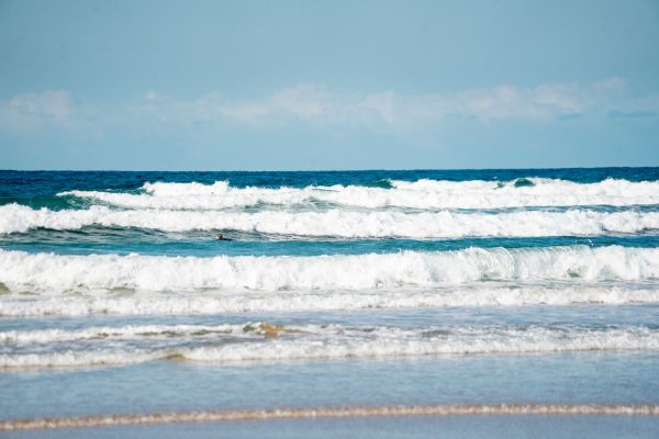 Vibrant ocean waves crashing on a sandy beach under a clear blue sky, capturing a breathtaking coastal view. Nature 4K