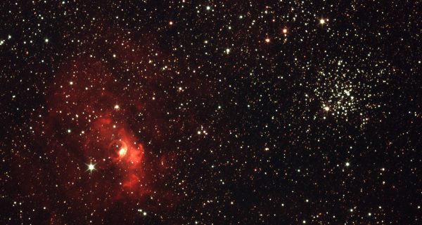 Vibrant photograph of the starry night sky featuring a bright red nebula and star clusters. Espace 4K