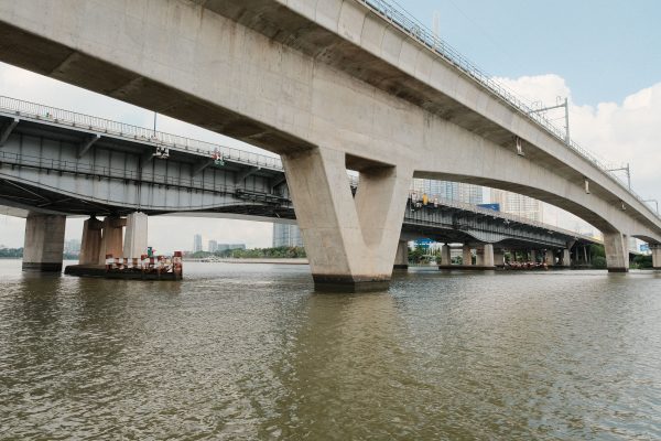 View of modern concrete bridge spanning over a river against a city backdrop. Architecture 4K