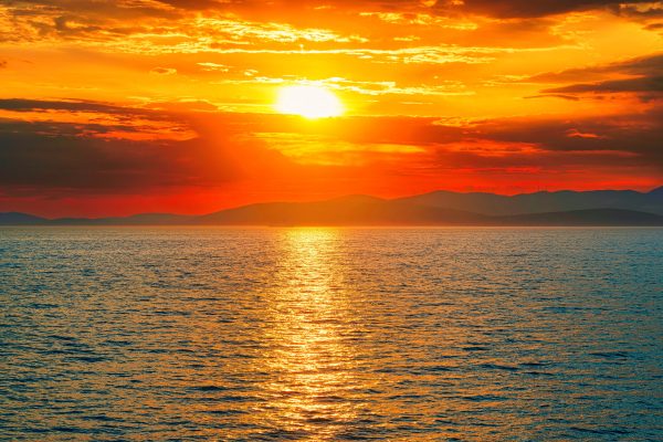 Vivid sunset over the ocean with dramatic orange sky and reflections. Nature 4K