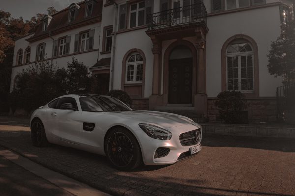 White luxury sports car parked outside a stylish residential home on a quiet street. Voitures 4K