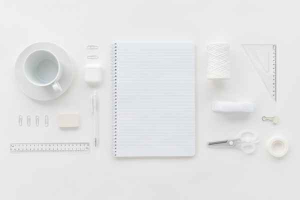 White-themed flat lay of office supplies including a notebook, cup, and stationery items. Minimaliste 4K