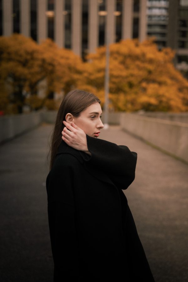 Woman in black coat with autumn background in urban setting. Mobile 4K