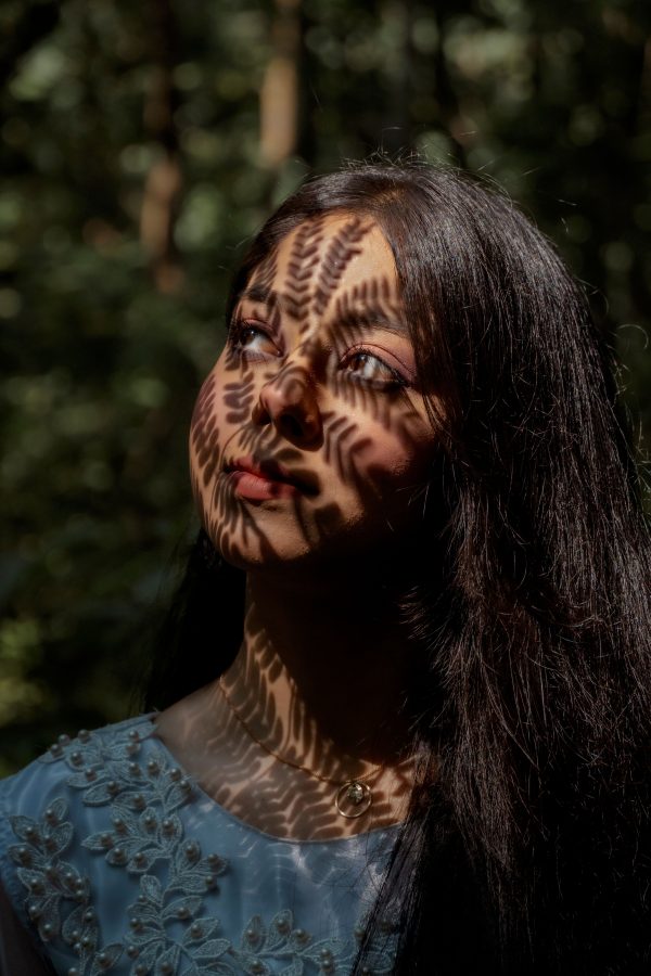 Woman with intricate leaf shadows on face in Dhaka forest. Captivating light play. Mobile 4K