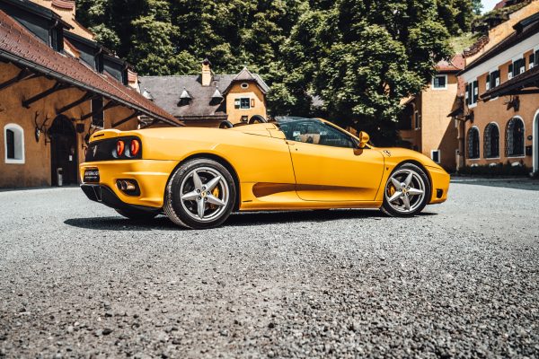 Yellow sports convertible parked in a historic courtyard, exuding elegance and style. Voitures 4K