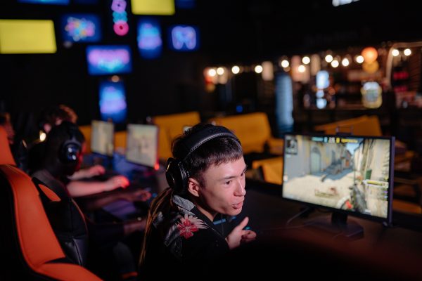 Young adults engaged in competitive gaming at an atmospheric cybercafe, sharing the esports experience. Gaming 4K
