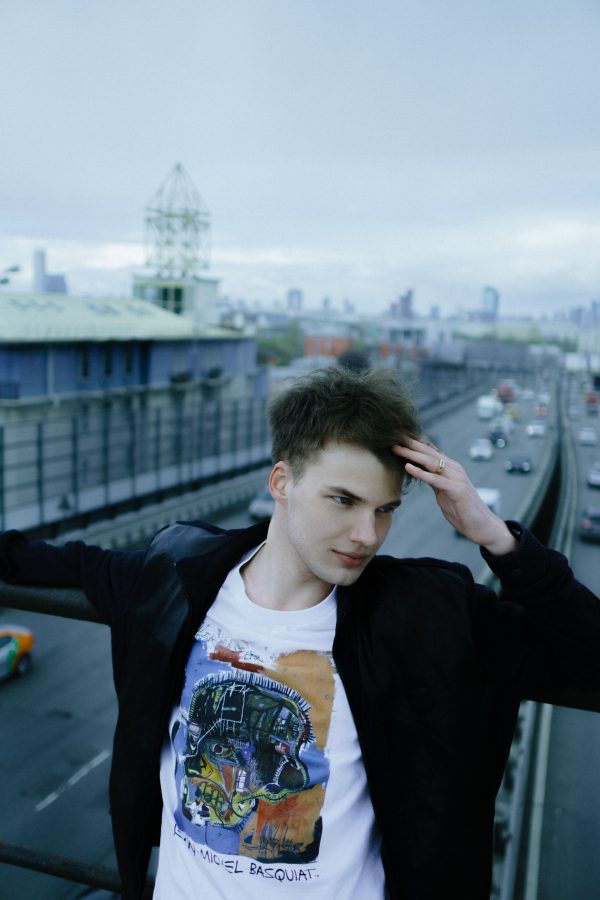 Young man in urban setting leaning on railing, day. Mobile 4K